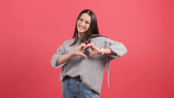 Happy Woman Put Make with Fingers Heart Shape, Isolated Over Red Background