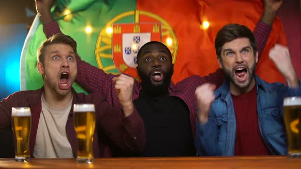 Cheerful Portuguese Multiracial Men Celebrating Soccer Team Victory, Waving Flag