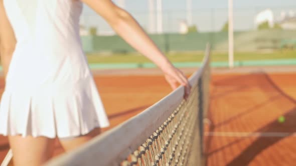 Woman Holds Her Hand on the Tennis Net