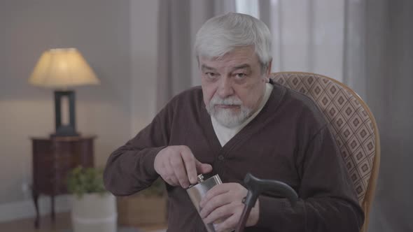 Portrait of Mature Caucasian Man Looking Around, Drinking Alcohol From Flask and Hiding It Back. Old