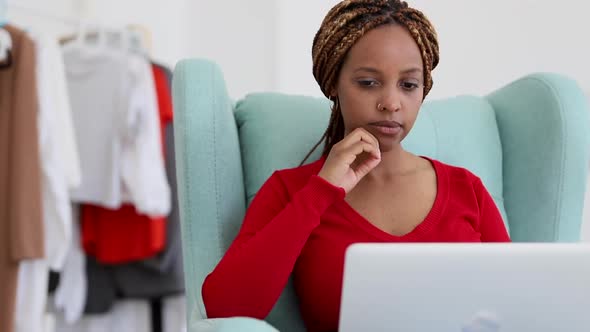 Young African American Woman is Using Laptop While Sitting in Armchair at Apartment Room Spbi