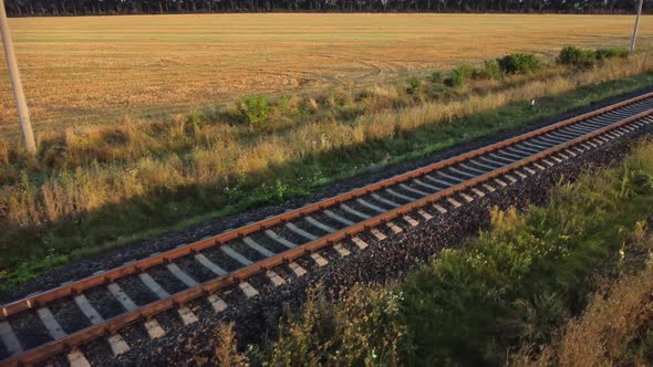 Railway tracks for industrial freight trains, road through agricultural field.