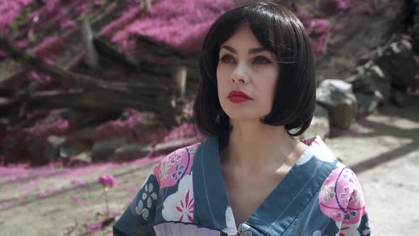 Steadicam Shot of Beautiful Caucasian Woman Dressed Like Japanese Geisha Standing Outdoors on Sakura