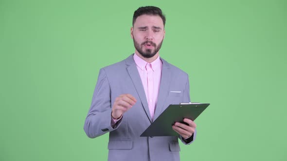 Happy Young Bearded Businessman Interviewing with Clipboard