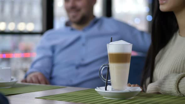 Closeup Waiter's Hands Putting Latte on Cafe Table