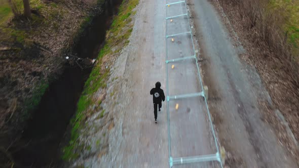 AERIAL chasing man running through forest looking for freedom