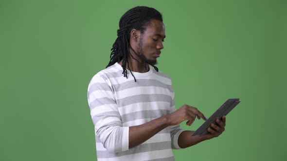 Young Handsome African Man with Dreadlocks Against Green Background