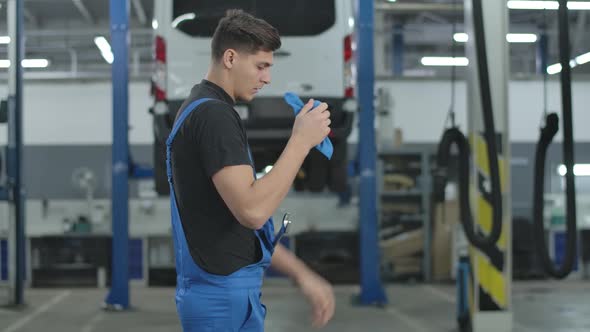 Serious Tired Auto Mechanic Cleaning Hands Throwing Cloth on Floor and Walking Away