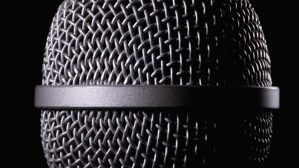 The Microphone Rotates on a Black Background. Dynamic Microphone Grid Spins Close-up