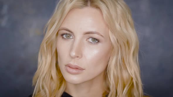 Portrait of a Blonde Model Posing Against Grey Wall