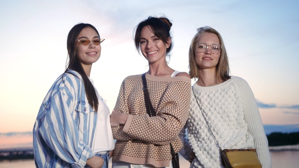 Three attractive female friends looking to camera posing