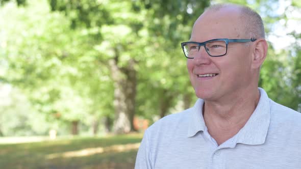 Happy Senior Man Smiling While Thinking At The Park