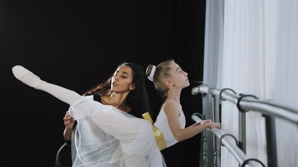 Female Teacher of Classical Dance Teaches Position Flexibility Stretching to Young Student Teen Girl