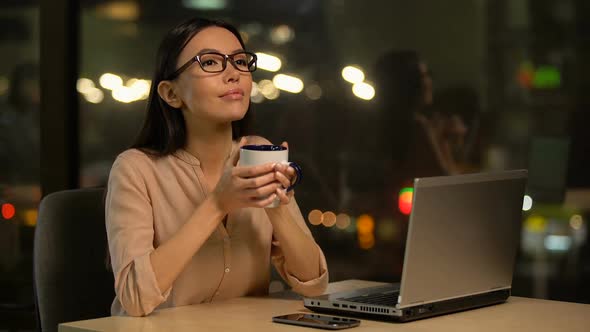Female Journalist Typing Article on Laptop, Drinking Coffee for Inspiration