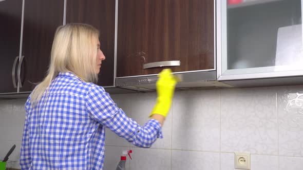 A woman cleans and polishes kitchen countertops with a spray