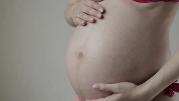 A Pregnant Girl Strokes Her Belly with Her Hands