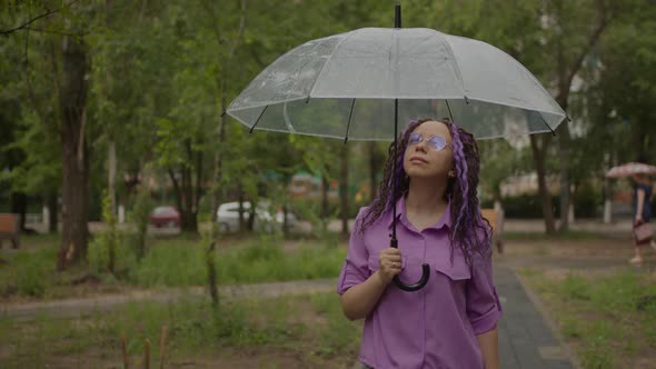 A woman with umbrella in hand in the rain.