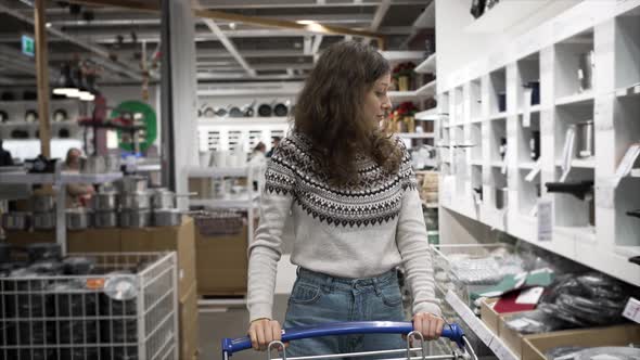 Wavyhaired Woman Walks in Mall with Shopping Trolley