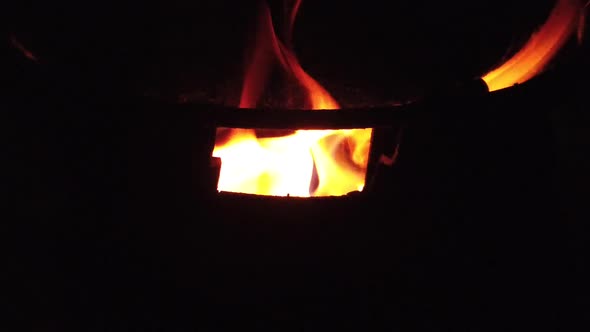 Slow motion burning wood logs on fire in a barrel at night