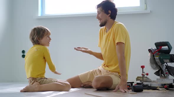 Father and His Little Son Install Laminate on the Floor in Their Apartment