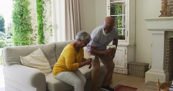 African american senior couple smiling while having coffee together sitting on the couch at home