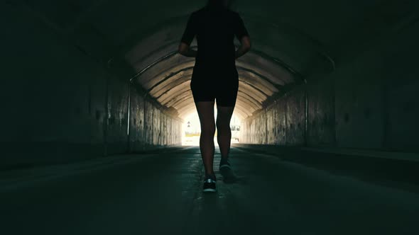 Woman Running in a Dark Tunnel to Meet the Light