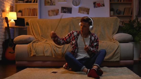 Excited Teenager in Headphones Listening to Music Pretending to Drums, Passion