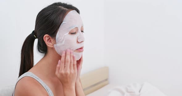 Woman apply paper mask on bed