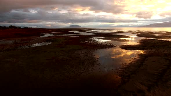 Flying low over shoreline of lake at sunset