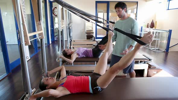 Two women doing pilates with male instructor