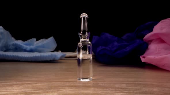 Vial with Transparent Liquid Stands on Brown Wooden Table