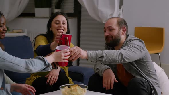 Multiethnic Friends Socializing During Night Home Party While Resting on Couch