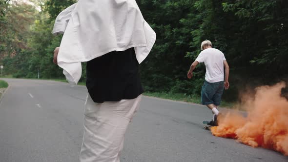 Young Progressive Skaters Ride Through the Park with a Smoke Bomb Attached to the Board