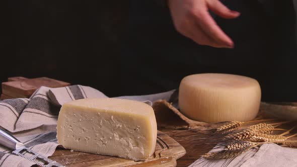 Women hands put pieces of  fresh homemade cheese on a wooden board close up