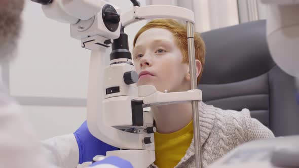 Little Redhead Boy Having Slit Lamp Exam in Ophthalmology Office