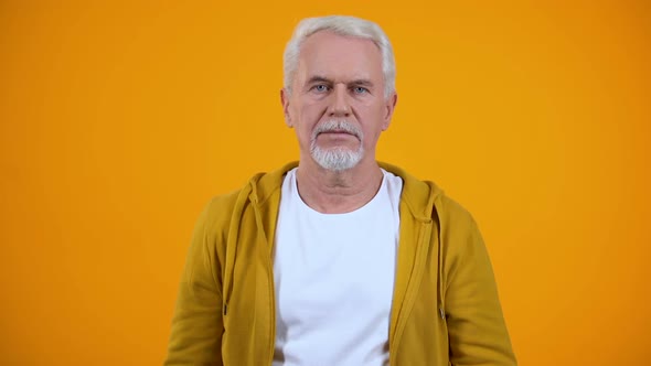Grey-Haired Pensioner Showing Silence Gesture Against Orange Background, Secret