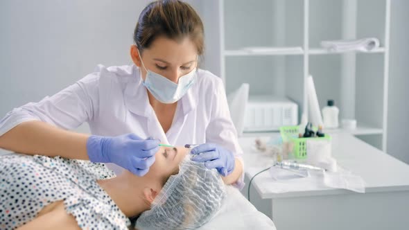 Woman Beautician Doing Degreasing Eyebrows Using Microbrush or Cotton Swab or Tampon