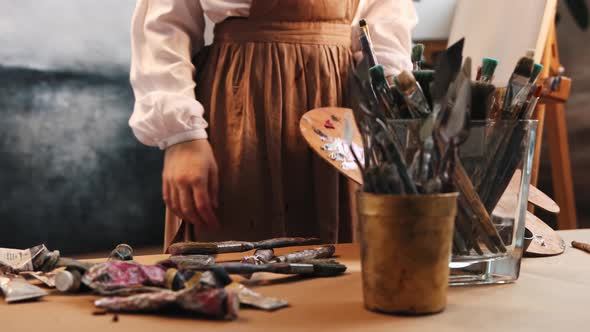 Art Studio  Young Woman Artist Walks to the Table and Takes Color Palette From It