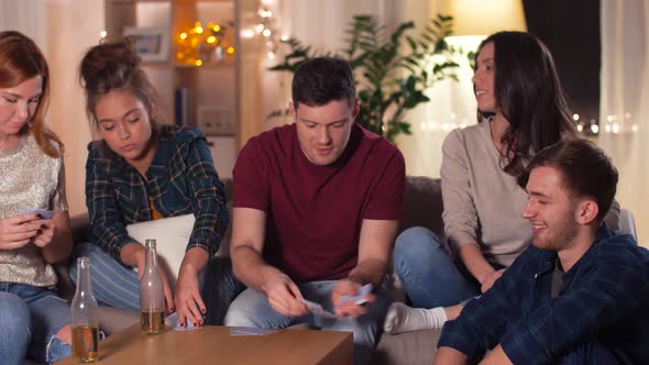 Friends Playing Cards Game at Home in Evening 