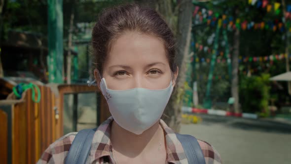 Young Woman in Protective Fashion Medical Mask on Her Face Looking at Camera Outdoors