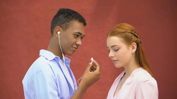 Teenager Sharing Earphones With Girlfriend Listening to Favorite Lyric Song