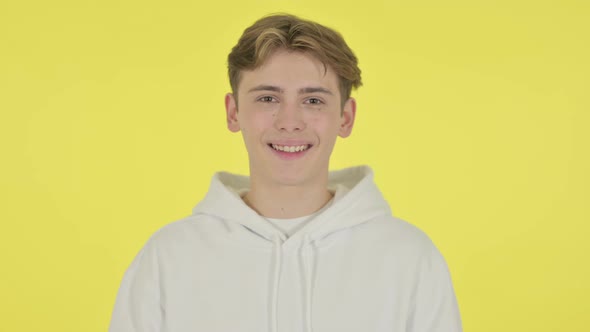 Young Man Smiling at Camera on Yellow Background