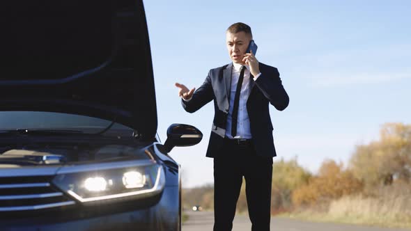 Man Use Smartphone Stading Near the Broken Car Opened the Hood Calling Car Assistance Services