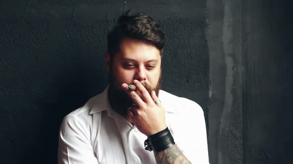 Male smoking cigarette. Bearded young man vaping with cigarette on background