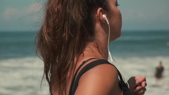 Woman in Earphones is Running Along Seashore