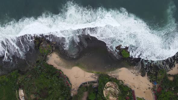 Top down aerial view of giant ocean waves crashing and foaming in coral beach