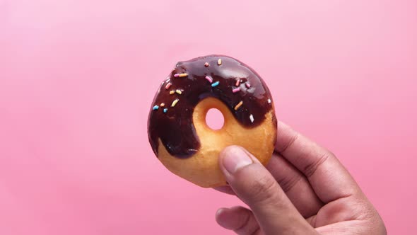 A Man Holds a Donut in Hand on a Pink Background