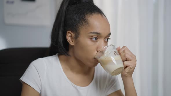 Closeup Portrait of Serious Young Woman Drinking Morning Coffee in Home Office Indoors