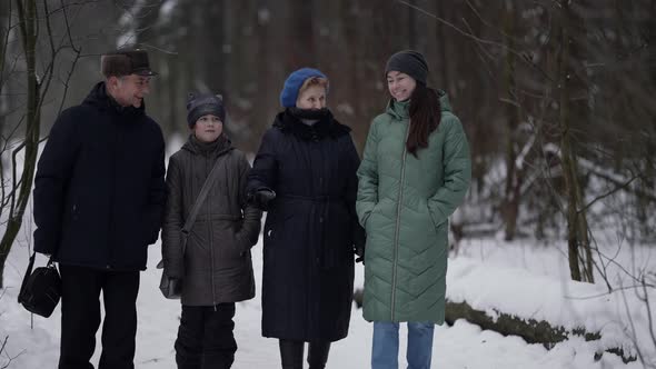 Little Girl and Her Mother and Grandparents are Walking in Park at Winter Happy Family