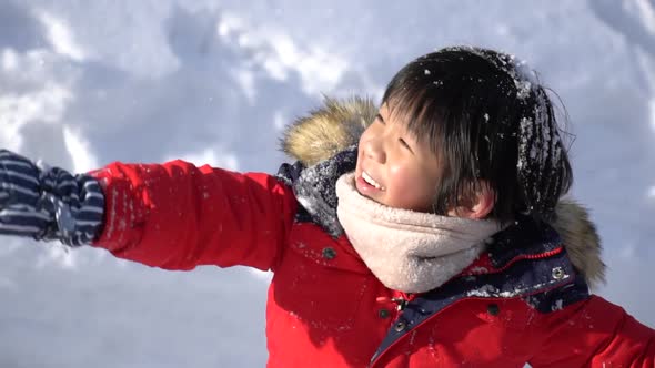 Cute Asian Child Wearing Winter Clothes Playing On Snow In The Park